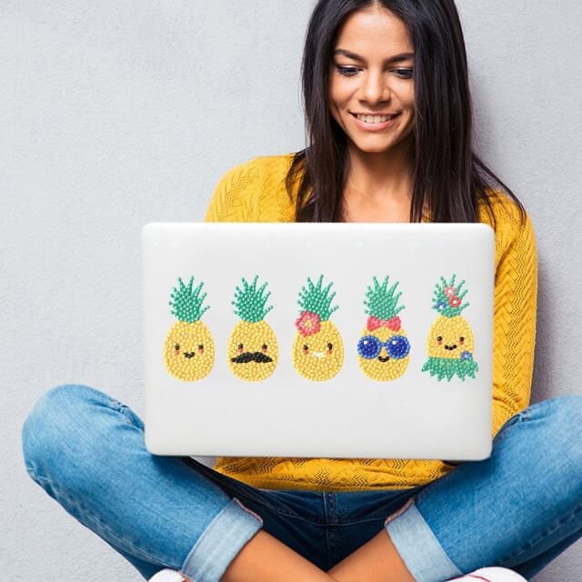 a woman and her laptop which has pineapple diamond painting stickers